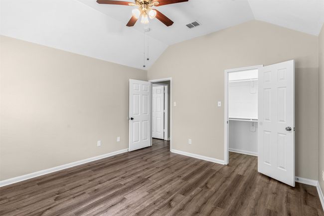 Unfurnished bedroom with visible vents, baseboards, wood finished floors, vaulted ceiling, and a spacious closet | Image 33