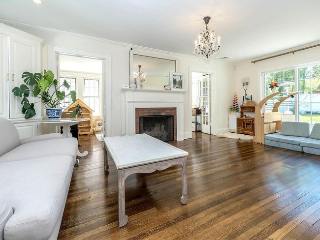 Living room with healthy amount of natural light, a chandelier, wood finished floors, a fireplace, and ornamental molding | Image 4