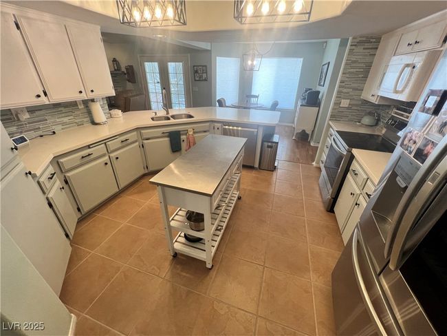 Kitchen featuring stainless steel appliances, a peninsula, backsplash, and light countertops | Image 16