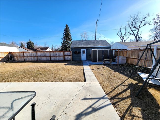 Rear view of house featuring a fenced backyard, a shingled roof, and an outdoor structure | Image 9
