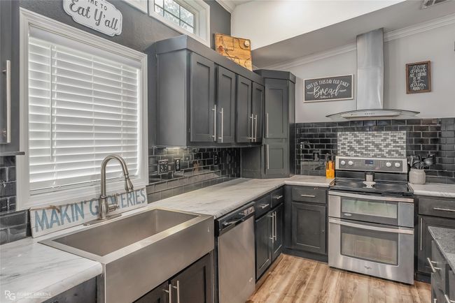 Kitchen featuring stainless steel appliances, crown molding, wall chimney range hood, and a sink | Image 19