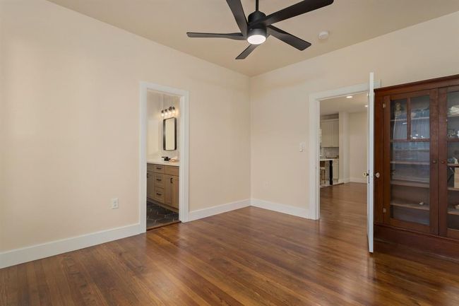 An alternate view of this spacious bedroom showcases an elegant glass-front built-in armior, restored original wood floors, and direct access to the convenient hollywood bathroom. | Image 29