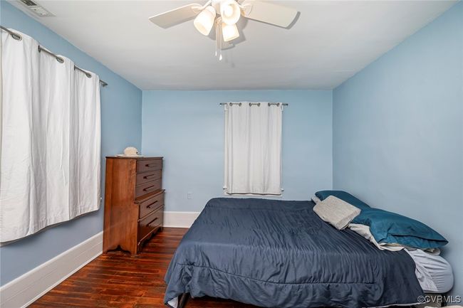Bedroom featuring a ceiling fan, baseboards, dark wood-style floors, and visible vents | Image 22