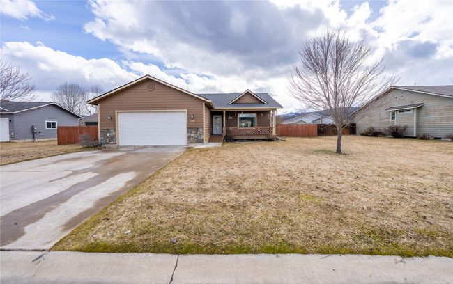 Single story home with stone siding, concrete driveway, a garage, and fence | Image 32