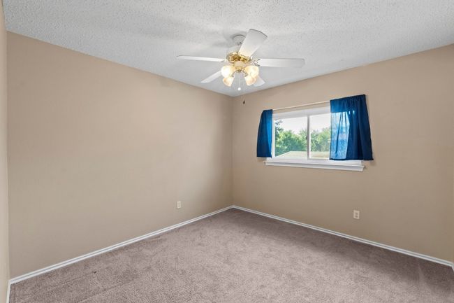 Empty room with carpet, a textured ceiling, ceiling fan, and baseboards | Image 27