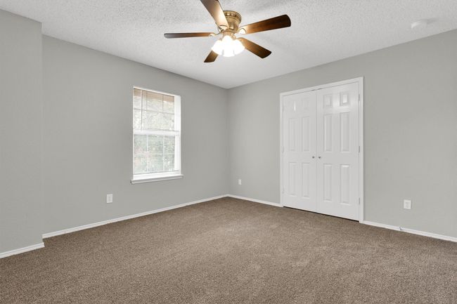 Unfurnished bedroom with carpet flooring, a closet, a textured ceiling, ceiling fan, and baseboards | Image 25