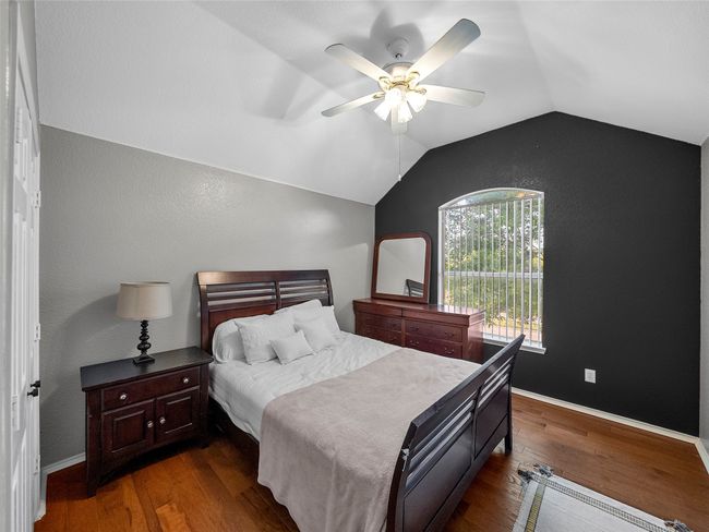 Bedroom with baseboards, lofted ceiling, a ceiling fan, and dark wood-style floors | Image 30