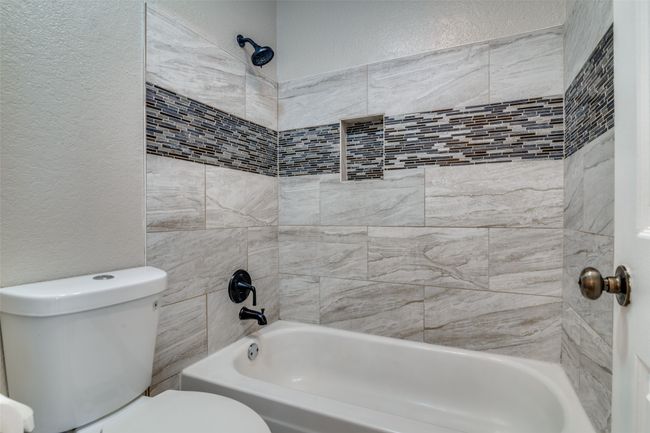Bathroom featuring a textured wall and shower / tub combination | Image 19