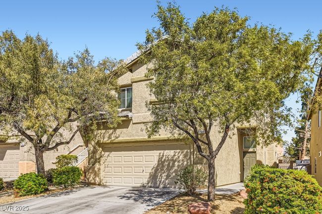 View of property hidden behind natural elements with driveway, an attached garage, and stucco siding | Image 26