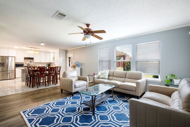 Living room featuring a textured ceiling, light wood-style flooring, a ceiling fan, and crown molding | Image 5