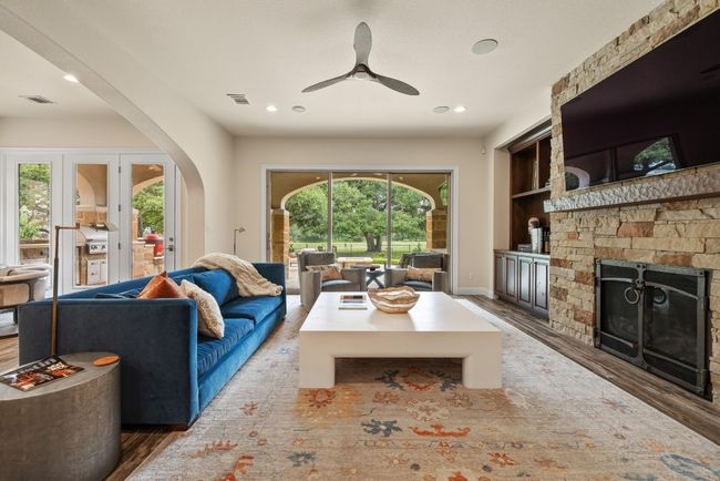 Living area with wood finished floors, a fireplace, ceiling fan, arched walkways, and recessed lighting | Image 8