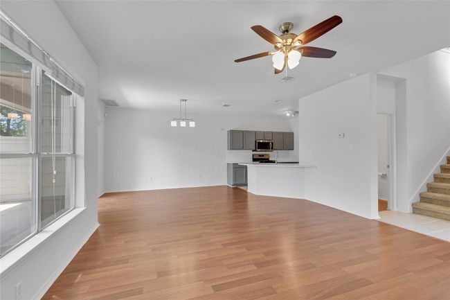 Unfurnished living room featuring ceiling fan, stairs, and light wood-style floors | Image 4