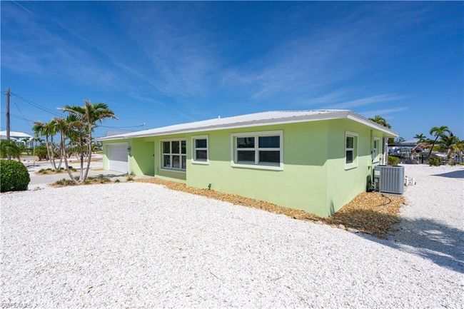 Rear view of property featuring gravel driveway, central AC, a garage, and stucco exterior. | Image 20