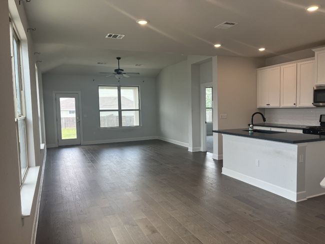 Kitchen with white cabinets, dark countertops, a sink, stainless steel microwave, and visible vents | Image 9
