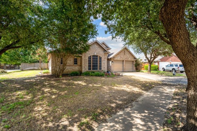 View of front facade featuring brick siding, driveway, and a garage | Image 4