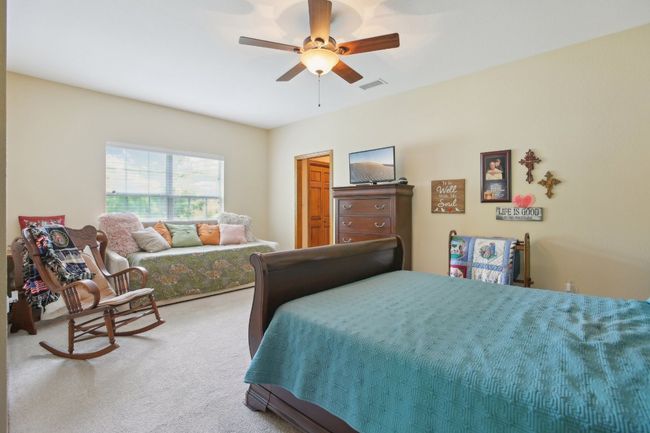 Bedroom featuring ceiling fan, visible vents, and light carpet | Image 12
