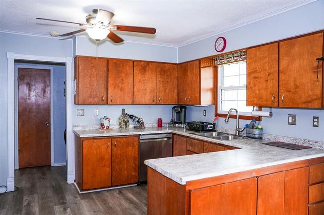 Kitchen with a sink, brown cabinetry, a ceiling fan, a peninsula, and stainless steel dishwasher | Image 6