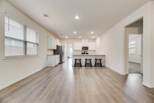 Kitchen with appliances with stainless steel finishes, light countertops, a kitchen breakfast bar, light wood-style flooring, and white cabinetry | Image 16