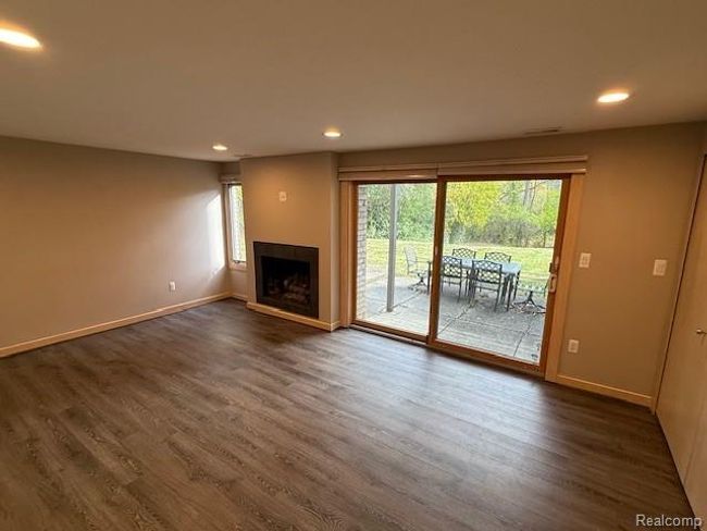 Unfurnished living room with recessed lighting, dark wood-style flooring, and a fireplace with raised hearth | Image 15