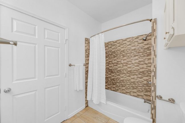 Full bathroom featuring shower / bath combination with curtain and tile patterned floors | Image 22