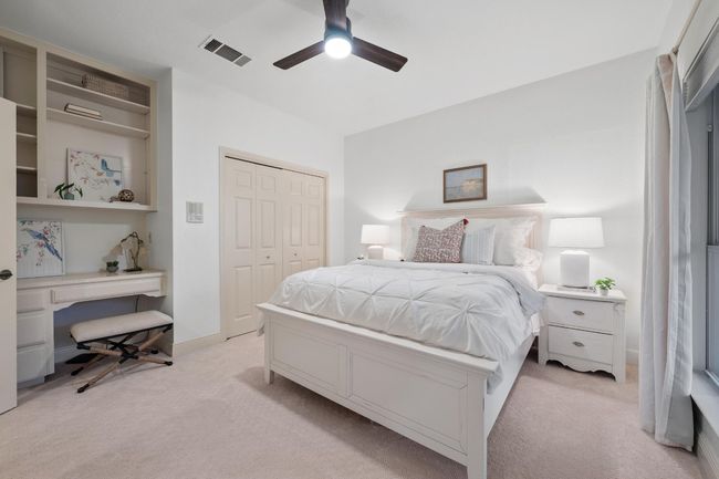 Bedroom with light colored carpet, a closet, a ceiling fan, and an office area | Image 24