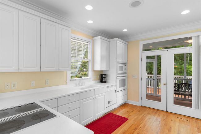 Kitchen with white appliances, french doors, a sink, white cabinetry, and ornamental molding | Image 5