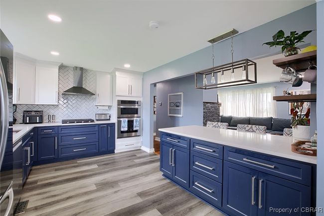 Kitchen featuring white cabinetry, wall chimney range hood, stainless steel appliances, and blue cabinets | Image 34