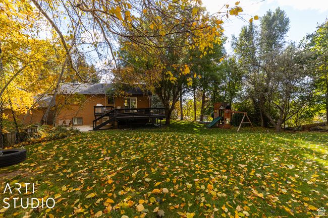 View of green lawn with a playground, a deck, and stairs | Image 47
