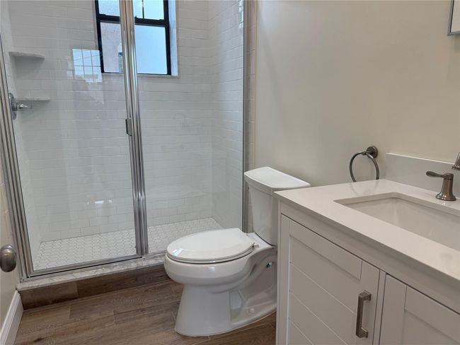 Full bathroom with wood finished floors, a shower stall, and vanity | Image 4