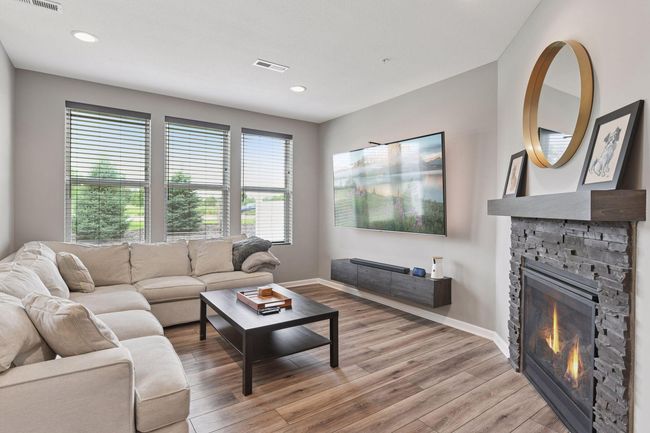 The Family Room features an inviting gas fireplace with stone surround and large windows that look out to the backyard. | Image 5