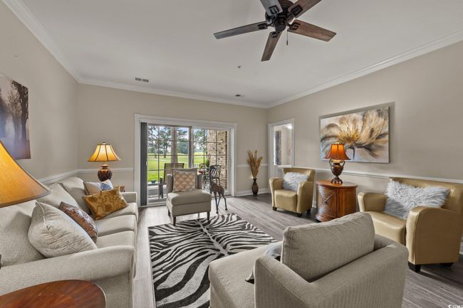 Living room with crown molding, light wood finished floors, a ceiling fan, and baseboards | Image 7
