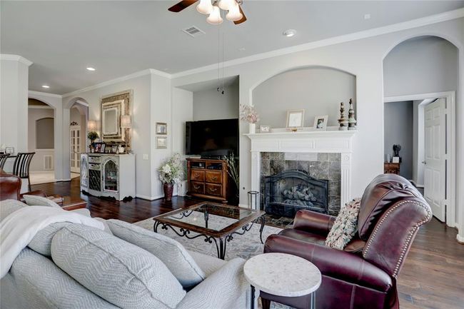 This is a spacious and elegantly appointed living room with hardwood floors, a cozy fireplace, arched doorways, and high ceilings. | Image 11