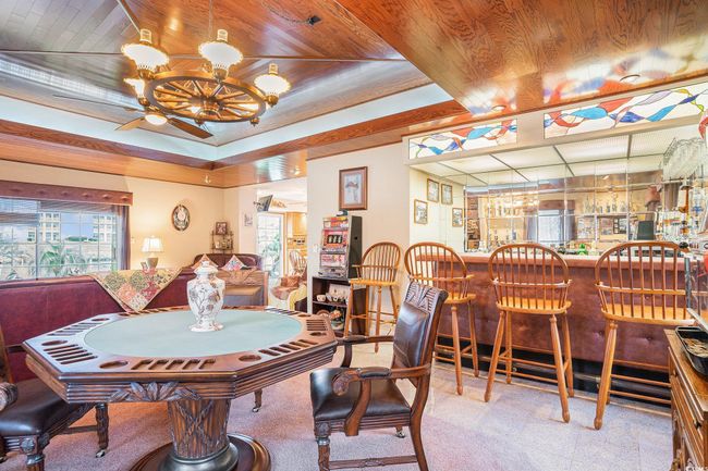 Carpeted dining space featuring a bar, a ceiling fan, and wooden ceiling | Image 17