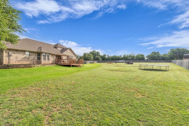 View of yard featuring a trampoline and a wooden deck | Image 34