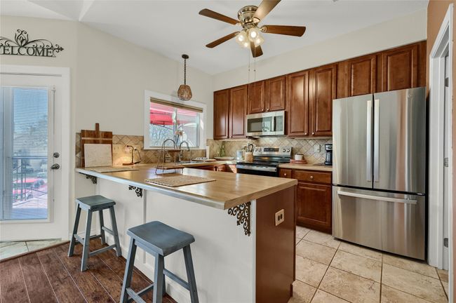 Kitchen with appliances with stainless steel finishes, a breakfast bar area, backsplash, and a peninsula | Image 7