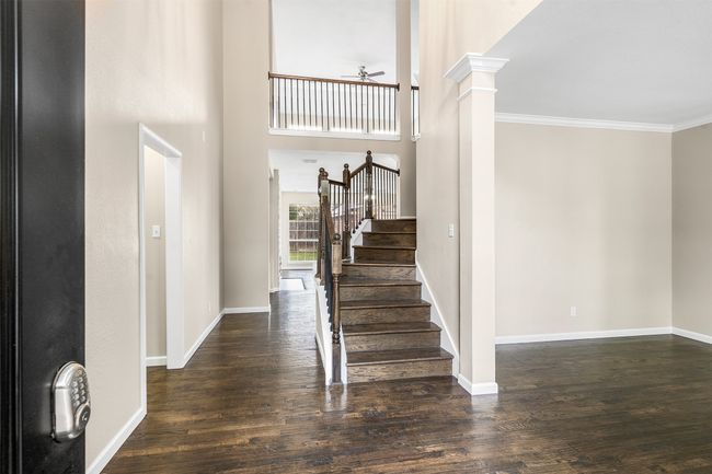 Entryway featuring crown molding, wood finished floors, stairway, and a ceiling fan | Image 5