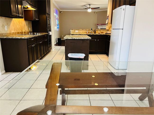 Kitchen with oven, white refrigerator, a center island, light tile patterned floors, and crown molding | Image 11