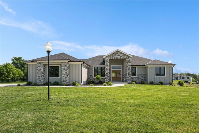 View of front of home featuring stone siding, a front lawn, and board and batten siding | Image 4