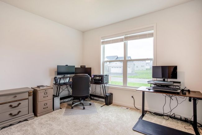 Bright and functional main-floor bedroom with oversized window, ideal for working from home in comfort and style. | Image 24