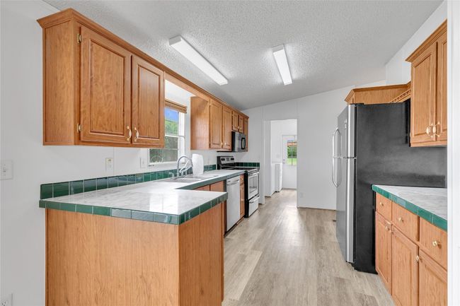 Kitchen featuring stainless steel appliances, light wood-style floors, a textured ceiling, plenty of natural light, and a peninsula | Image 14
