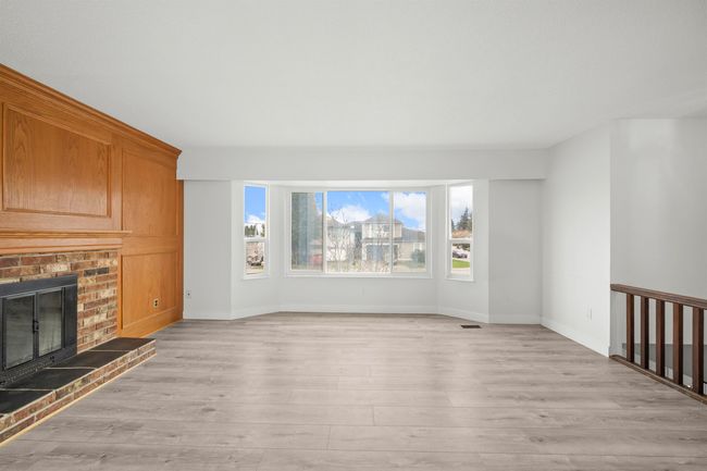Unfurnished living room featuring baseboards, a fireplace, and light wood-style flooring | Image 4