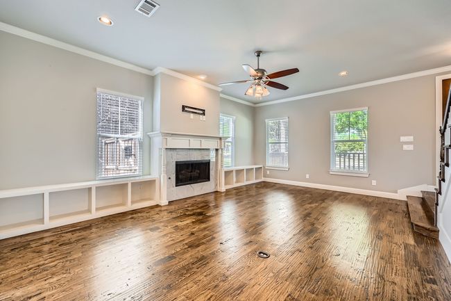 Living room featuring wood finished floors, ceiling fan, crown molding, a fireplace, and plenty of natural light | Image 5