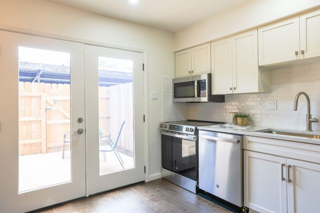 Kitchen with stainless steel appliances, decorative backsplash, dark engineered hardwood style flooring, light quartz countertops, and recessed lighting. | Image 14