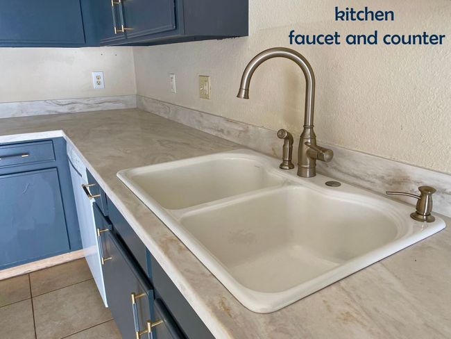 Room details with blue cabinets, a textured wall, light countertops, and a sink | Image 9