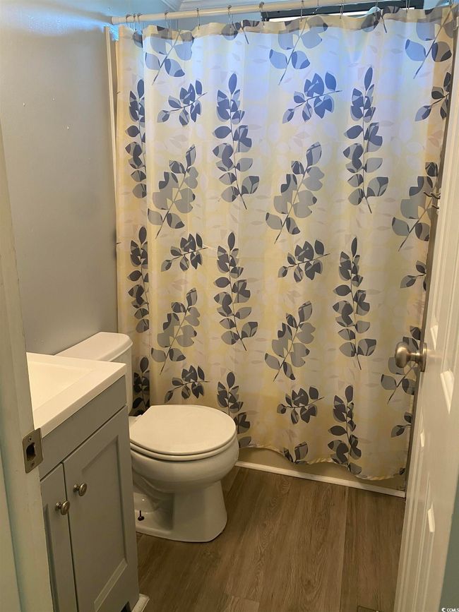 Full bathroom with wood finished floors, vanity, and curtained shower | Image 18