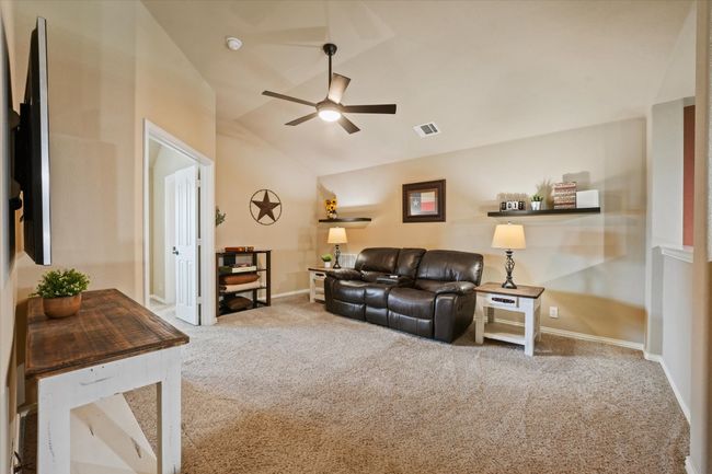 Carpeted living area with vaulted ceiling, visible vents, baseboards, and ceiling fan | Image 31