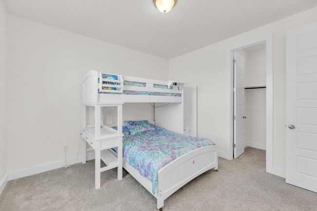 Bedroom with a spacious closet, baseboards, and light colored carpet | Image 28