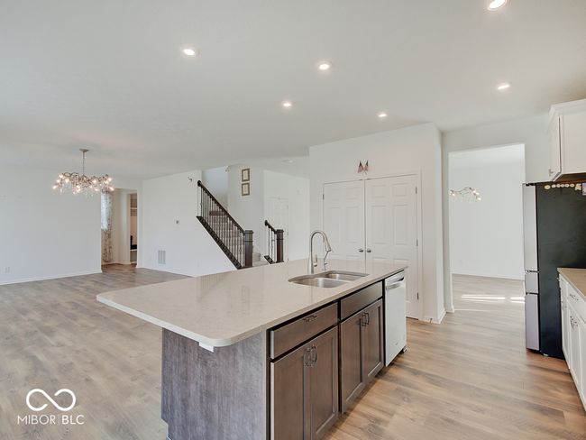 Kitchen featuring recess can lighting, island w/ sink, laminate flooring, stainless steel appliances including double oven, gas cooktop, microwave w/ hood vented to outside, dishwasher, refrigerator, & pantry | Image 17