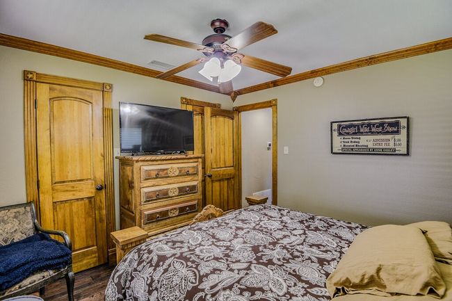 Bedroom featuring dark wood finished floors, crown molding, and ceiling fan | Image 23