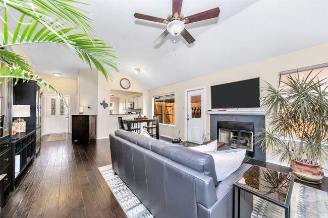 Living area featuring a ceiling fan, dark wood-type flooring, a tile fireplace, vaulted ceiling, and baseboards | Image 12